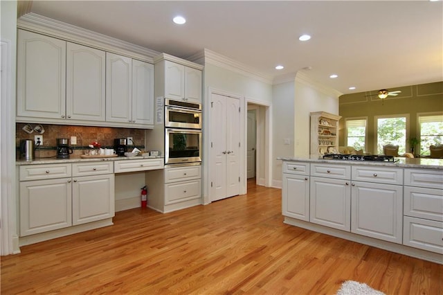 kitchen with white cabinets, tasteful backsplash, light wood-type flooring, crown molding, and stainless steel appliances