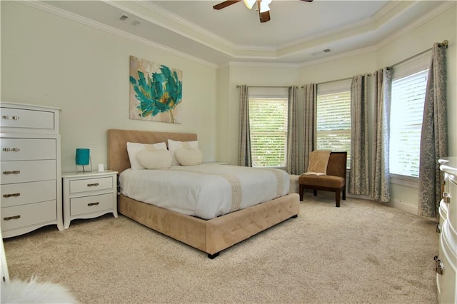 carpeted bedroom featuring ornamental molding, multiple windows, a tray ceiling, and ceiling fan