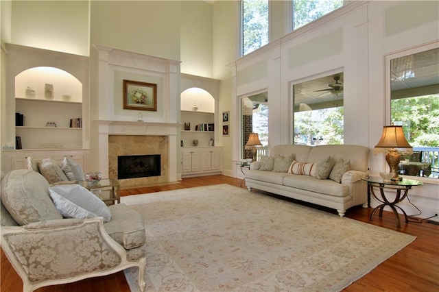 living room featuring a towering ceiling, hardwood / wood-style floors, built in features, and plenty of natural light