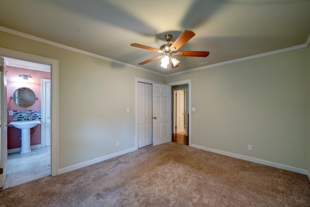 unfurnished bedroom with a closet, light colored carpet, ornamental molding, connected bathroom, and baseboards