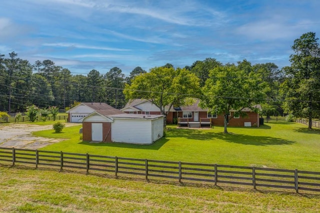 view of yard featuring a garage, fence, an outdoor structure, and a rural view