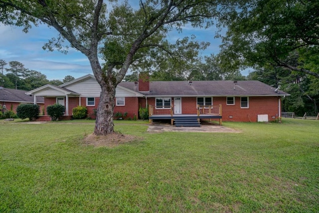 rear view of house with a wooden deck, a chimney, crawl space, a yard, and brick siding