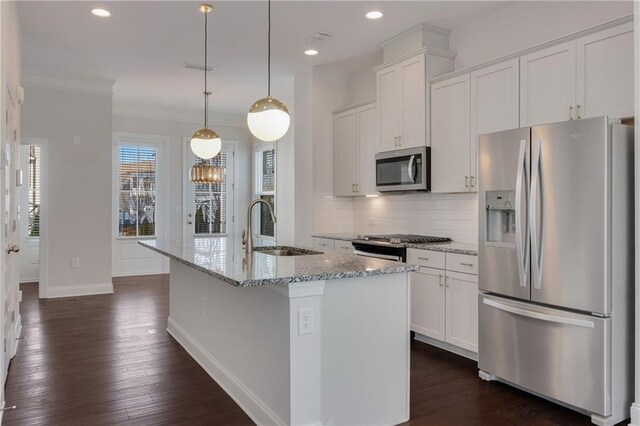 kitchen with stainless steel appliances, a sink, white cabinetry, decorative backsplash, and an island with sink