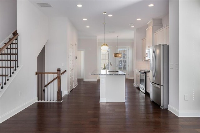 kitchen featuring stainless steel appliances, visible vents, tasteful backsplash, dark wood finished floors, and a center island with sink