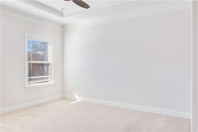 spare room with baseboards, a tray ceiling, ornamental molding, and light colored carpet