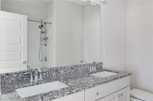 full bath featuring a shower, a sink, toilet, and double vanity