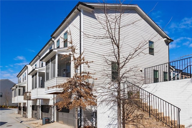 view of property exterior featuring stairs, driveway, an attached garage, and cooling unit