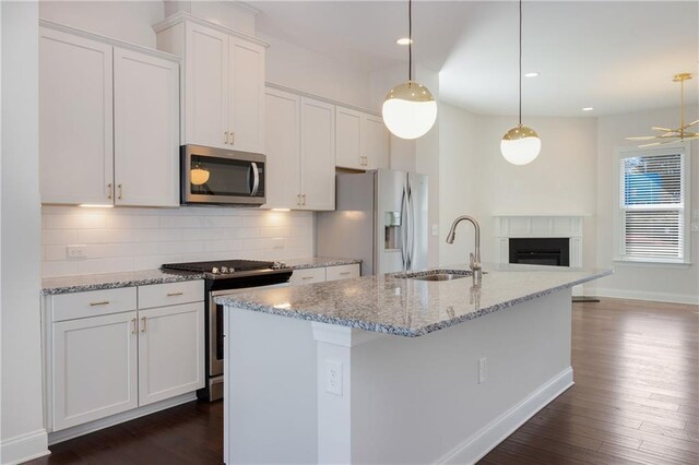 kitchen featuring dark wood-style floors, stainless steel appliances, decorative backsplash, white cabinetry, and a sink