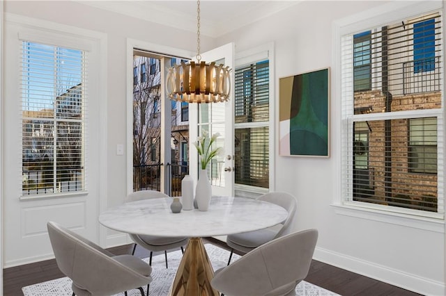 dining area with baseboards, ornamental molding, dark wood-type flooring, a healthy amount of sunlight, and a chandelier