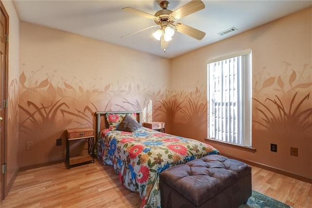bedroom featuring light wood-type flooring, visible vents, baseboards, and ceiling fan