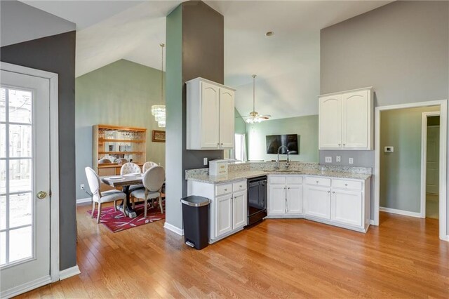 kitchen with white cabinets, light wood-style floors, black dishwasher, and high vaulted ceiling