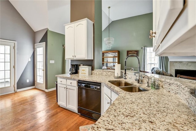 kitchen featuring black dishwasher, light stone counters, high vaulted ceiling, and a sink