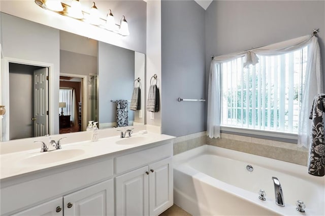 bathroom with double vanity, a bath, and a sink