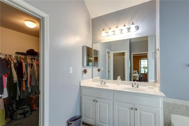 ensuite bathroom featuring ensuite bathroom, double vanity, a sink, and vaulted ceiling