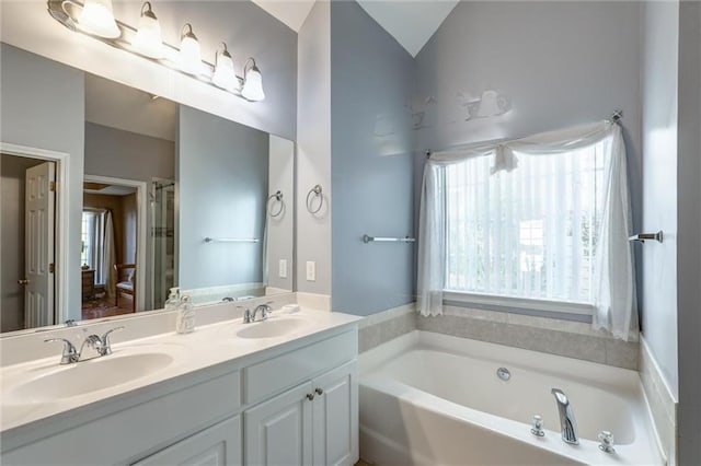 full bath with a sink, double vanity, and a bath