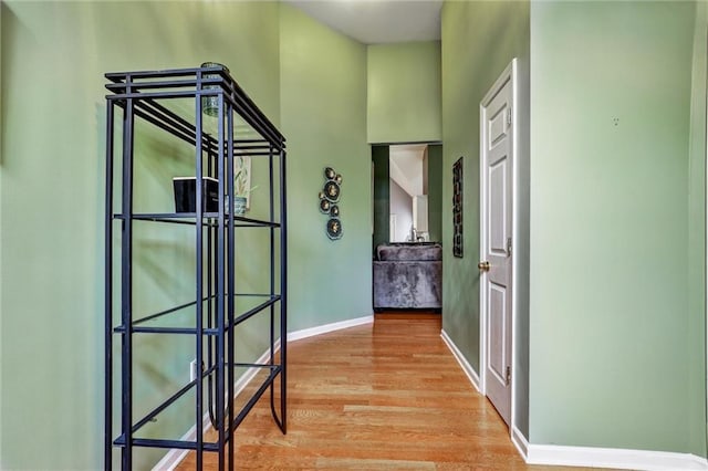 hallway featuring light wood finished floors and baseboards
