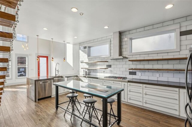 kitchen with decorative backsplash, appliances with stainless steel finishes, wall chimney range hood, and white cabinets