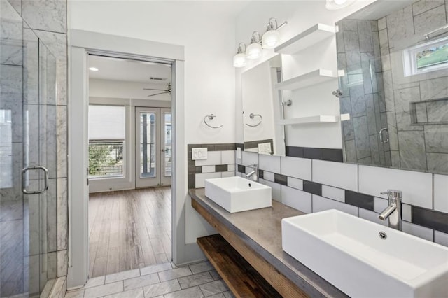 bathroom with ceiling fan, tile walls, vanity, decorative backsplash, and a shower with shower door