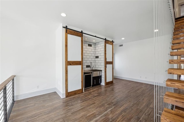 unfurnished living room with dark wood-type flooring and a barn door