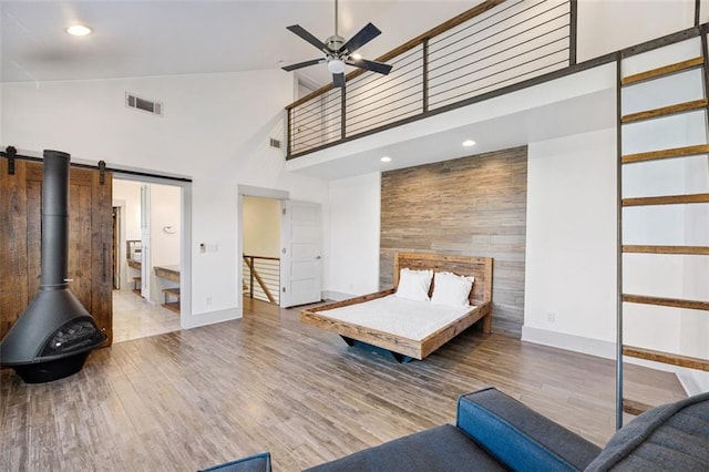 unfurnished bedroom with hardwood / wood-style flooring, a barn door, and a high ceiling