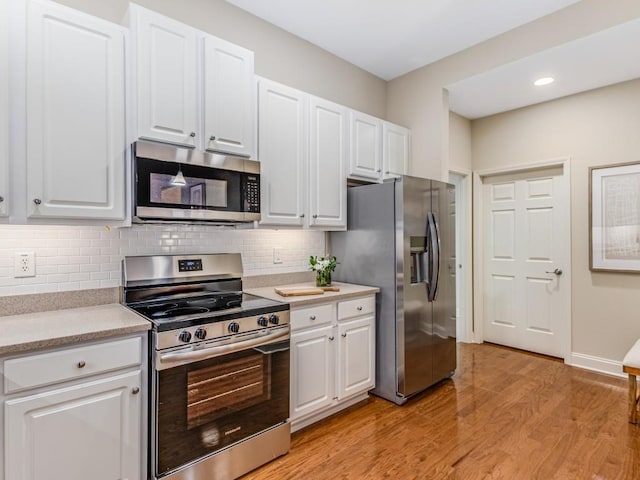 kitchen with stainless steel appliances, white cabinetry, light hardwood / wood-style flooring, and tasteful backsplash