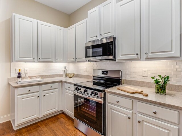 kitchen featuring light hardwood / wood-style floors, white cabinets, decorative backsplash, and appliances with stainless steel finishes