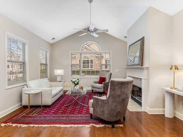 living room featuring ceiling fan, wood-type flooring, a premium fireplace, and vaulted ceiling