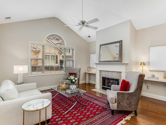 living room with ceiling fan, lofted ceiling, dark wood-type flooring, and a tiled fireplace