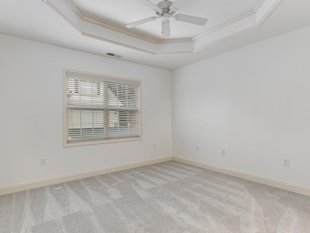 carpeted empty room featuring ceiling fan, a raised ceiling, and ornamental molding