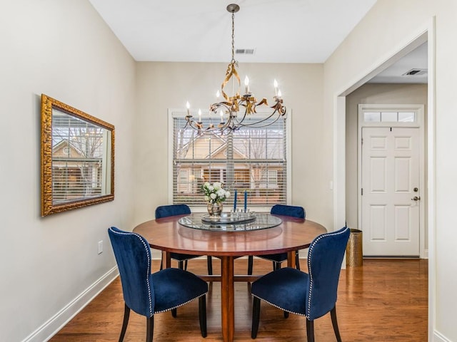 dining room with dark hardwood / wood-style floors and an inviting chandelier