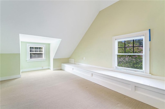 additional living space with light colored carpet and vaulted ceiling