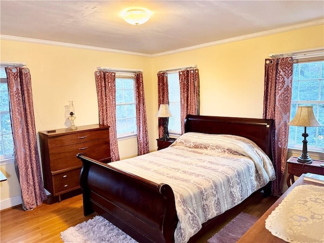 bedroom featuring multiple windows, hardwood / wood-style flooring, and ornamental molding