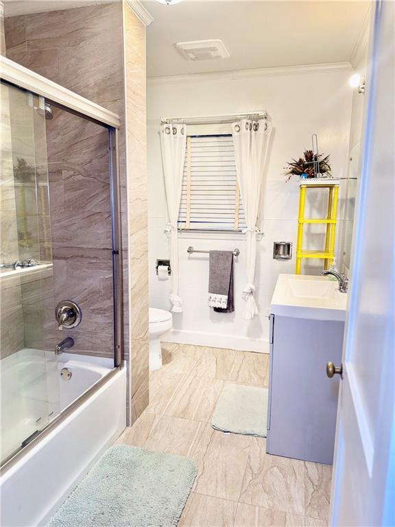 full bathroom with crown molding, vanity, toilet, and combined bath / shower with glass door