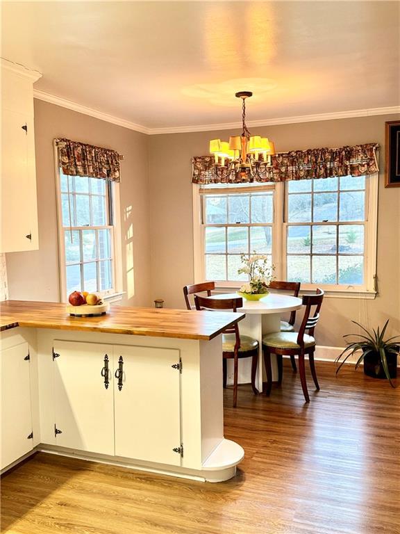 kitchen featuring hardwood / wood-style floors, pendant lighting, white cabinets, a chandelier, and ornamental molding