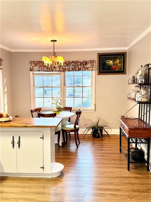 dining room with ornamental molding, an inviting chandelier, and light hardwood / wood-style flooring