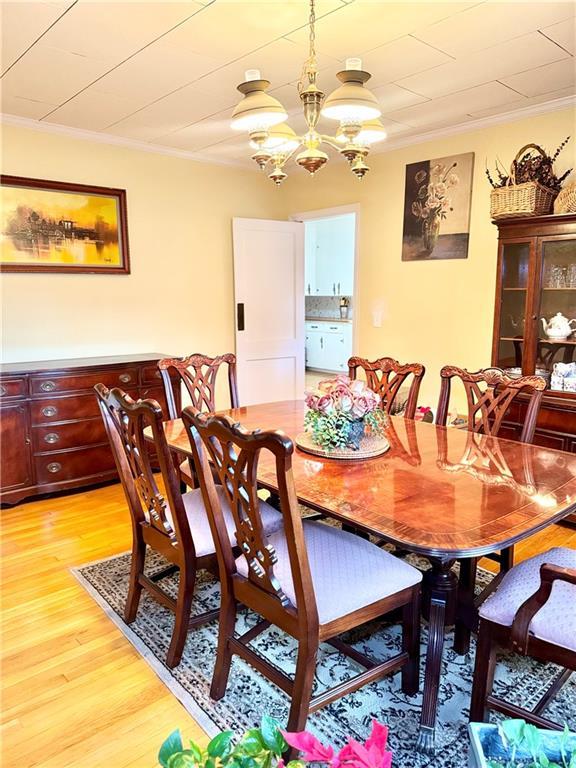 dining room featuring ornamental molding, light hardwood / wood-style floors, and a notable chandelier