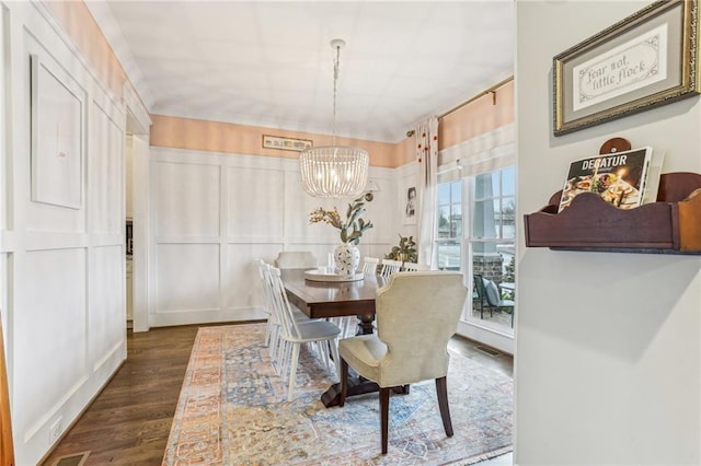 dining space with dark wood-type flooring and a notable chandelier