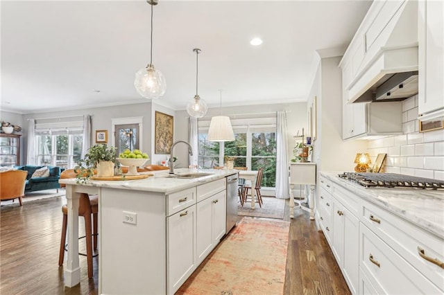 kitchen featuring sink, white cabinetry, backsplash, stainless steel appliances, and a center island with sink