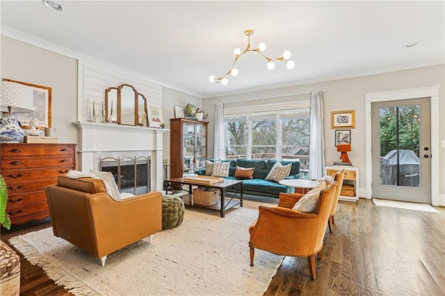 living room with an inviting chandelier, wood-type flooring, ornamental molding, and a healthy amount of sunlight