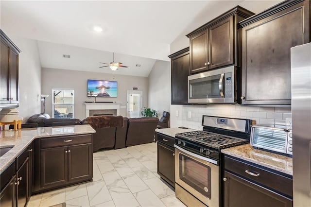 kitchen featuring lofted ceiling, ceiling fan, backsplash, stainless steel appliances, and dark brown cabinetry