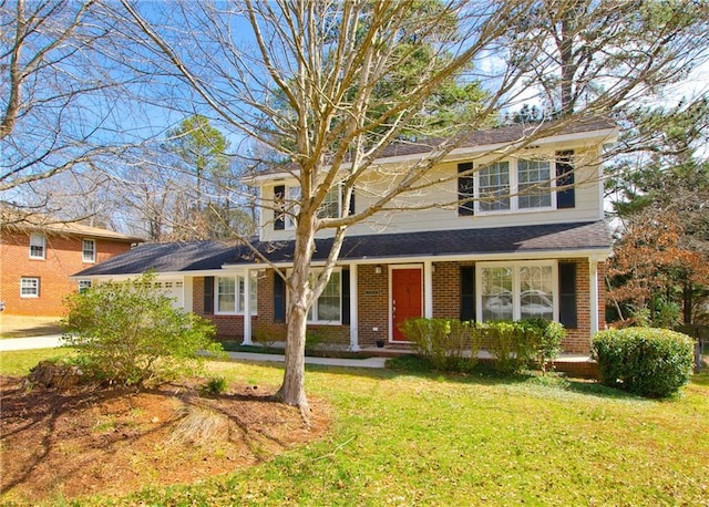 traditional-style house featuring brick siding, an attached garage, and a front lawn