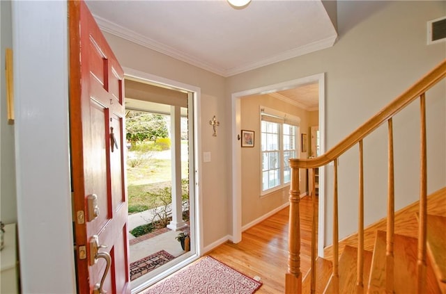 foyer entrance with visible vents, crown molding, baseboards, stairs, and light wood-style floors