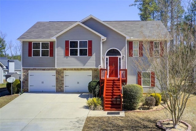 raised ranch with stone siding, driveway, and a garage