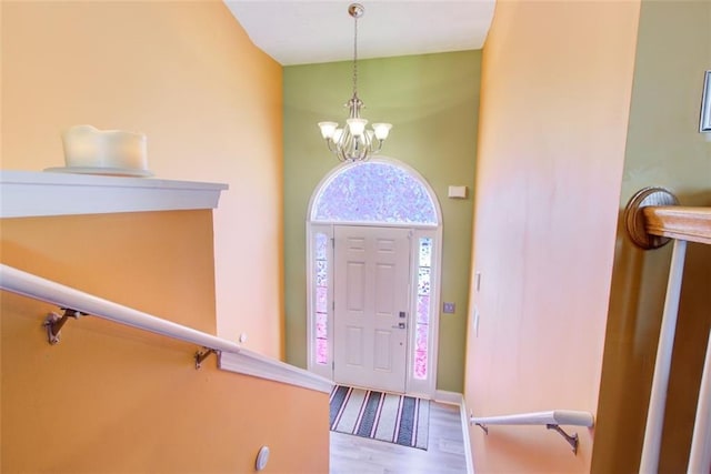 entryway with an inviting chandelier, wood finished floors, and baseboards