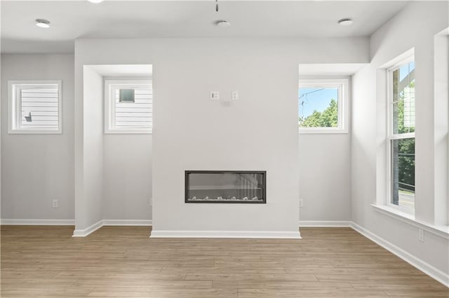 unfurnished living room featuring plenty of natural light and light wood-type flooring