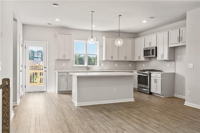 kitchen with light wood-type flooring, stainless steel appliances, and white cabinets