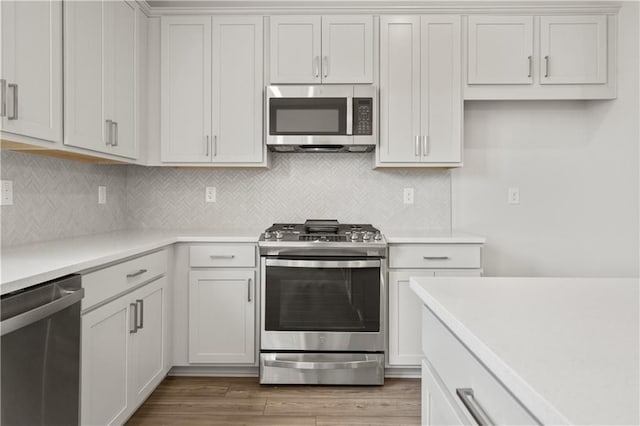 kitchen with stainless steel appliances, light wood-type flooring, and white cabinetry