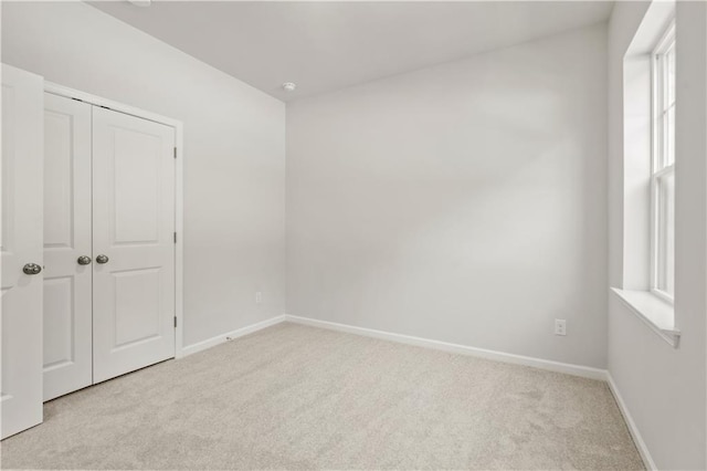 unfurnished bedroom with light colored carpet and a closet