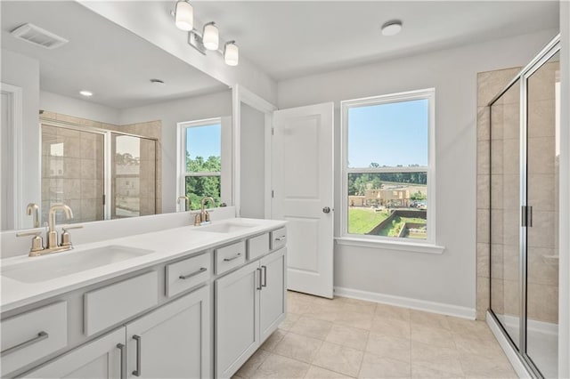 bathroom with a shower with door, vanity, and a healthy amount of sunlight