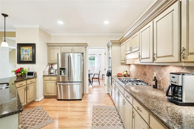 kitchen with cream cabinets, decorative light fixtures, light wood finished floors, and stainless steel appliances
